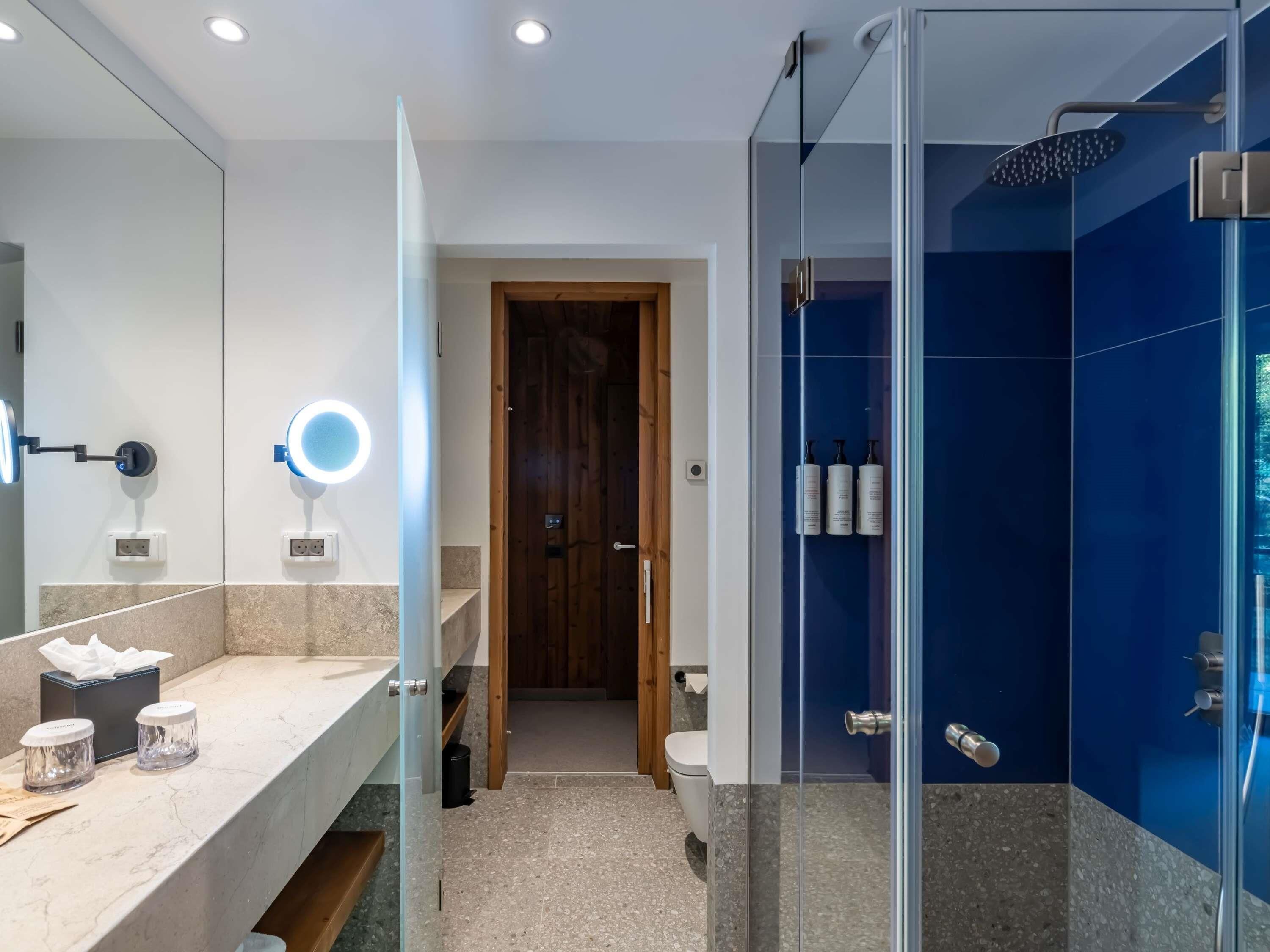 Un baño moderno con tocador, espejo y ducha.