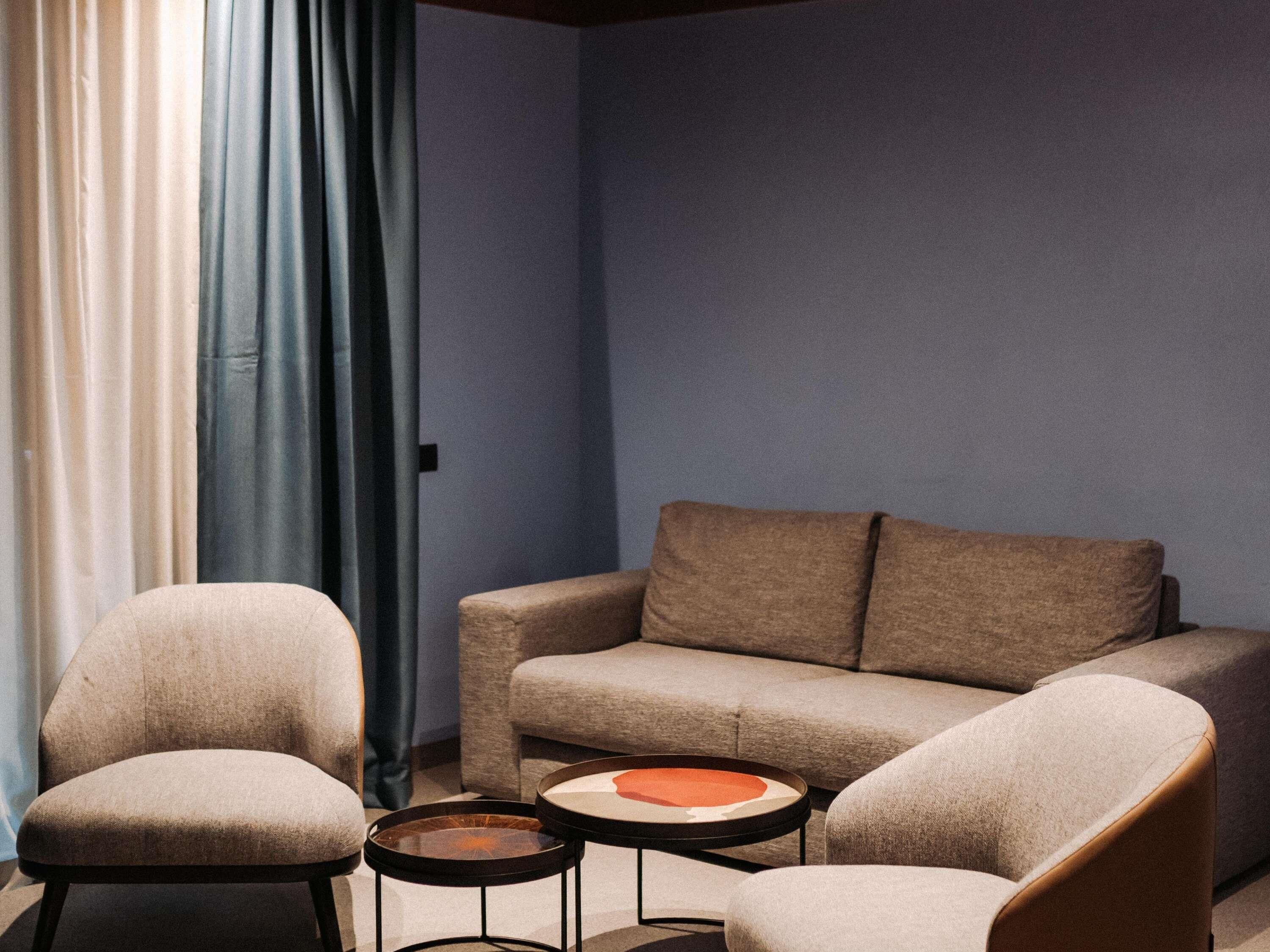 Ein Zimmer mit einer Couch, zwei Sesseln und zwei kleinen runden Tischen.
