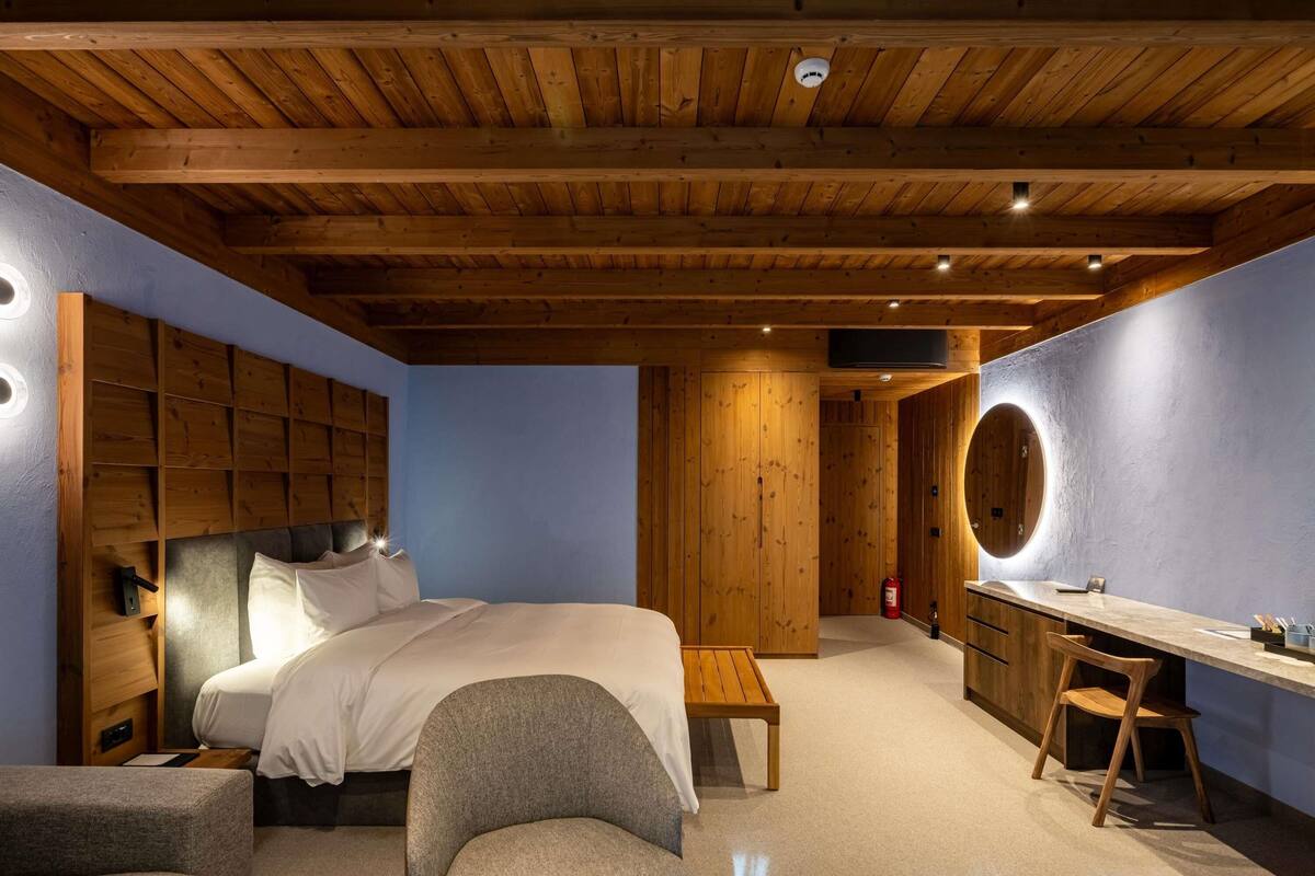 Ein Schlafzimmer mit Holzboden, einem Bett, einem Schreibtisch und einem Stuhl.