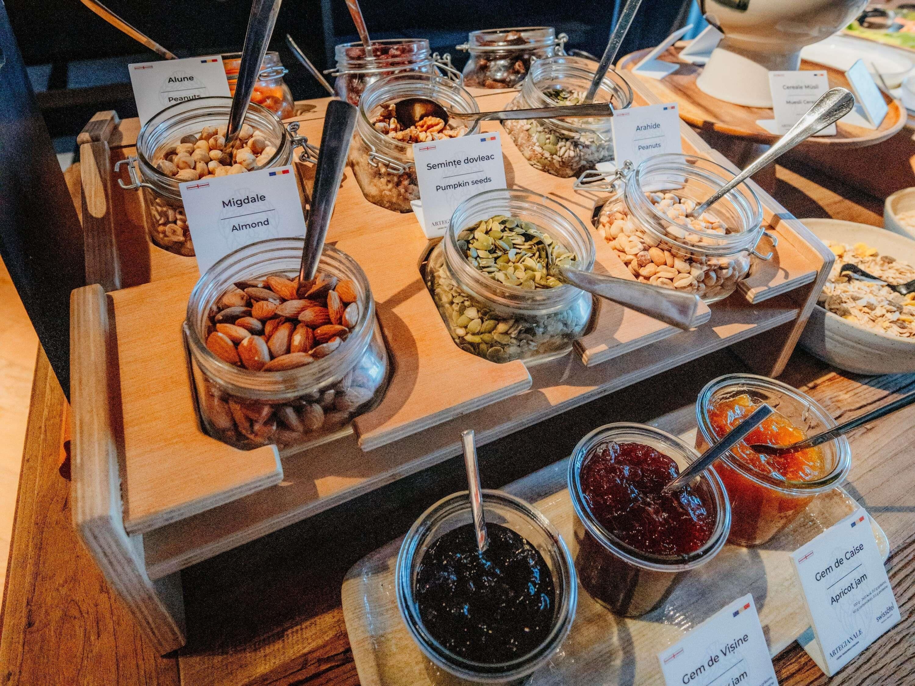 A buffet with various food items in jars, including almonds, pumpkin seeds, and different types of jams.