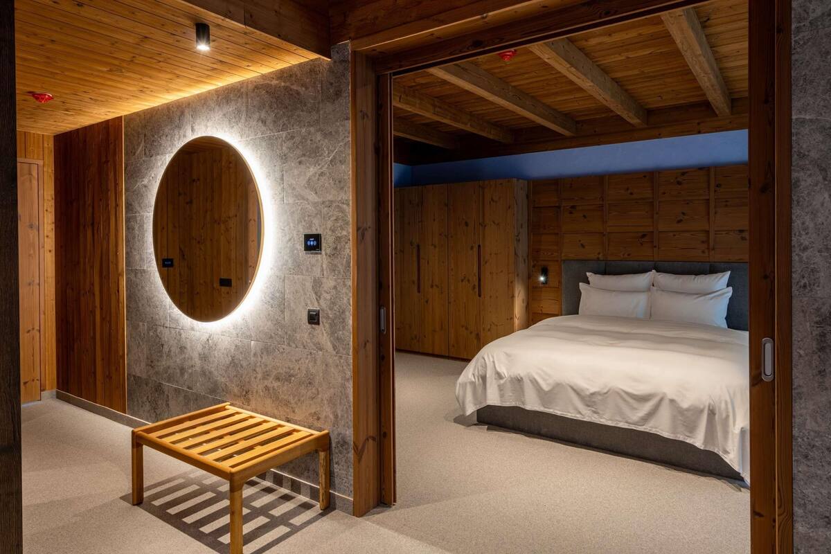 Ein Schlafzimmer mit einem Bett, einer Sitzbank, einer runden Leuchte und Holzwänden.