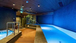 Uma área de spa com um deck de madeira, uma banheira de hidromassagem e uma piscina grande.