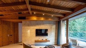 Uma sala de estar moderna com parede de pedra, teto de madeira e uma janela grande.