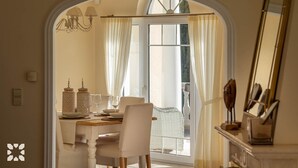 A dining area with a table set for two, a chandelier, and a view of the outdoors through a window with curtains. - Villa Marcela by Abahana Villas (Teulada)