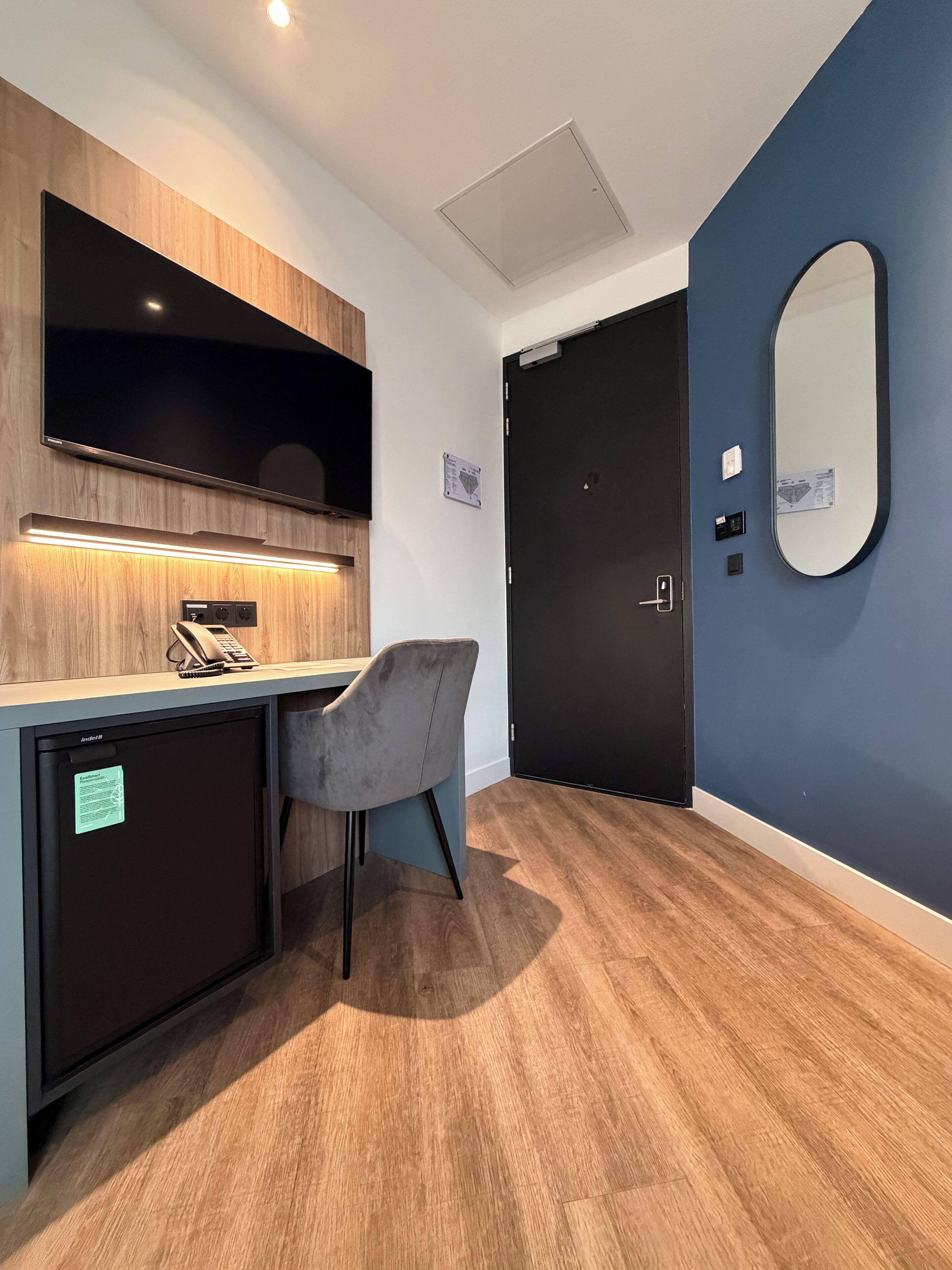 Una habitación moderna con escritorio, silla y un espejo grande en la pared.