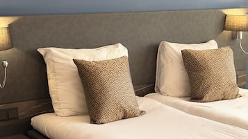 Una cama doble con almohadas estampadas, un cabecero, lámparas de noche y una mesita de noche.