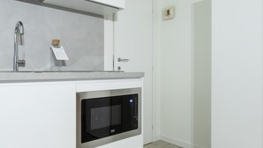 A modern kitchen with white cabinetry, a stainless steel sink, and a built-in oven.