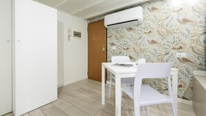 A small, clean room with a white table and chairs, an air conditioning unit, and a wooden door.