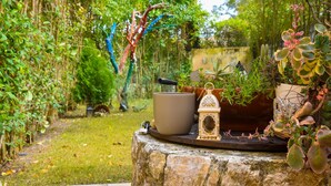 A garden with potted plants, a stone bench, and a lantern.