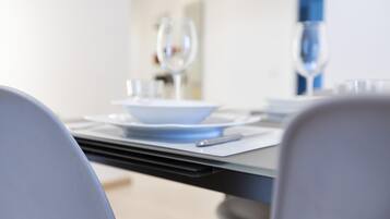 A dining table set with plates, cutlery, and glasses, with a chair in the foreground.