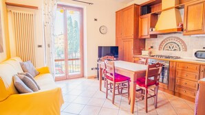 A compact living space with a dining area, kitchen, and a sofa with cushions. - Al Bivio Peschiera - Italian Homing (Peschiera del Garda)