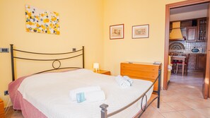 A hotel room with a bed, a wooden dresser, a nightstand, and a small table. There are two framed pictures on the wall. - Al Bivio Peschiera - Italian Homing (Peschiera del Garda)