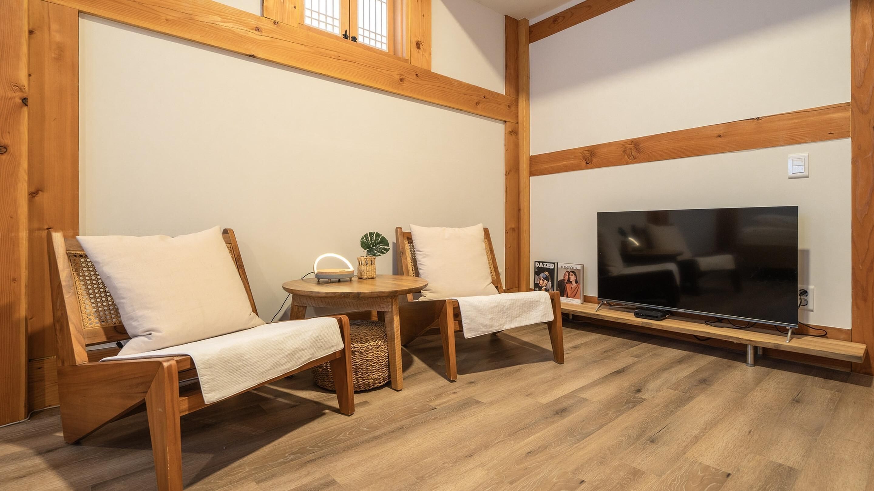 A cozy room with wooden furniture, a TV, and a small table with a plant.