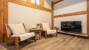 Una habitación acogedora con muebles de madera, un televisor y una mesita con una planta.