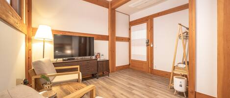 A room with a wooden ceiling, a television, a sofa, a small table, and a traditional Japanese sliding door.