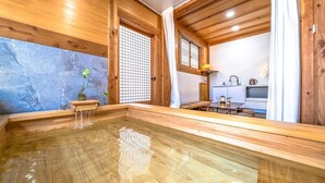 Perinteinen japanilainen onsen-kylpylä, jossa on puusisustus, pieni pesuallas ja keittiöalue.