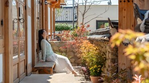 Un edificio de estilo japonés tradicional con fachada de madera, muro de piedra y tejado de tejas.