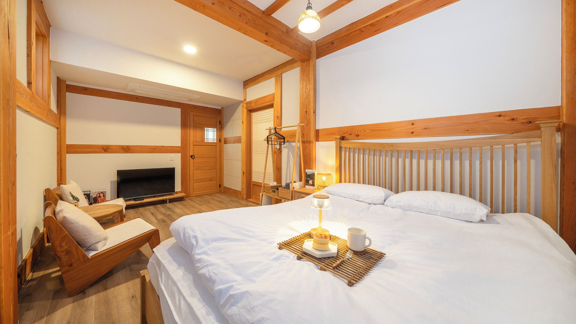 A bedroom with a bed, bedside table, lamp, and a television.