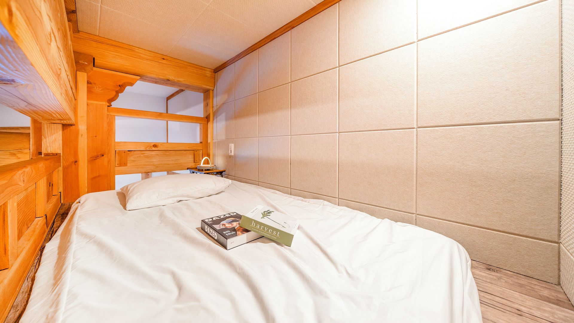 A wooden-framed room with a bed, a nightstand, and a window.