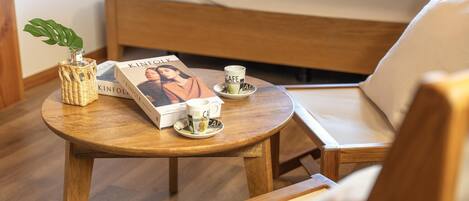 Un tavolino in legno con un libro, due tazze e una pianta.