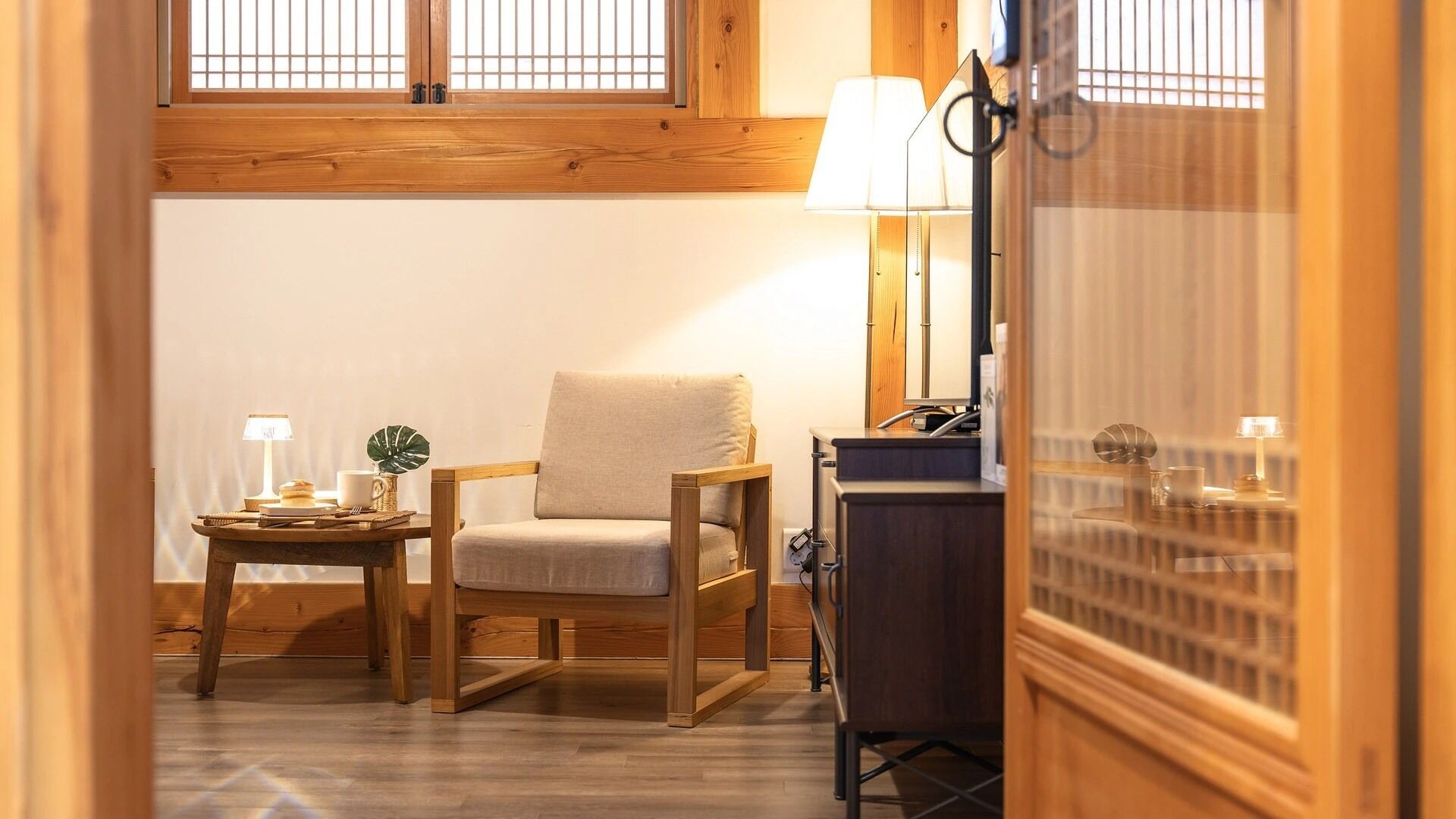 Une pièce confortable avec une chaise en bois, une petite table avec une lampe et un bureau également doté d’une lampe.