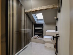 A modern bathroom with a skylight, a black towel, and a white sink. - 8 Oak Cottages (Lancaster)