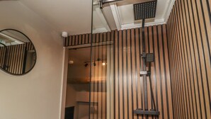 Une petite chambre comprenant un lit, une douche et un miroir.