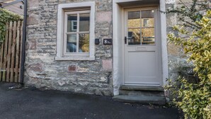 Un bâtiment en pierre avec une porte blanche et une fenêtre.