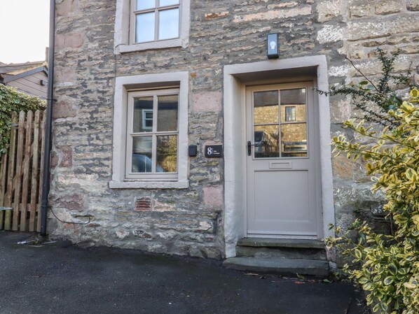 A stone building with a white door and a window. - 8 Oak Cottages (Lancaster)