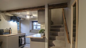 Une cuisine dotée d’un îlot central, d’un four encastré et d’un escalier menant à une mezzanine.