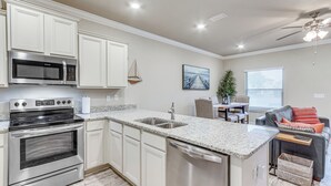 A modern kitchen with white cabinetry, stainless steel appliances, and a granite countertop. - Pensacola Vacation Rental w/ Community Pool! (Pensacola)