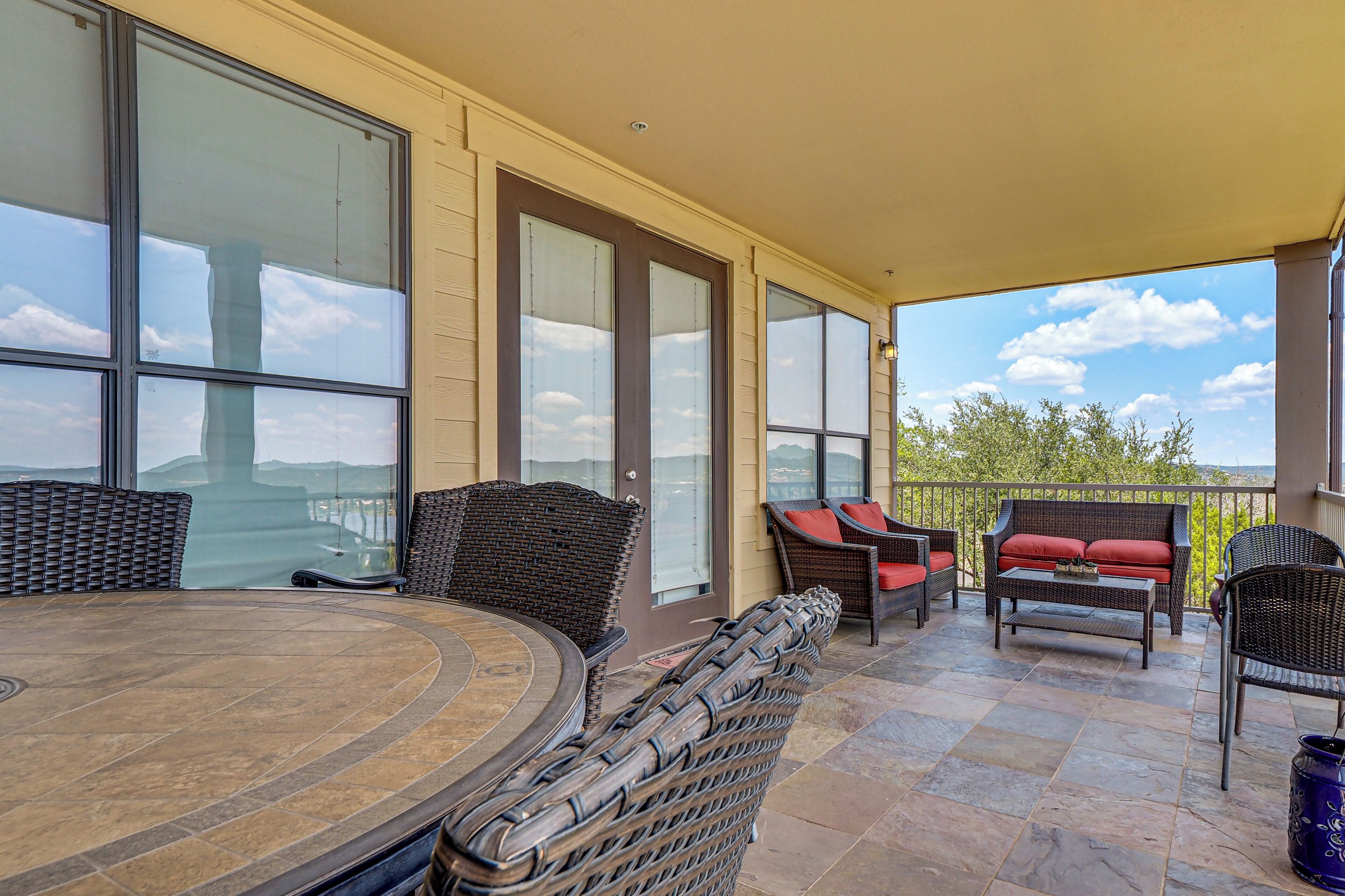 A covered patio with wicker furniture, a round table, and a view of the landscape.