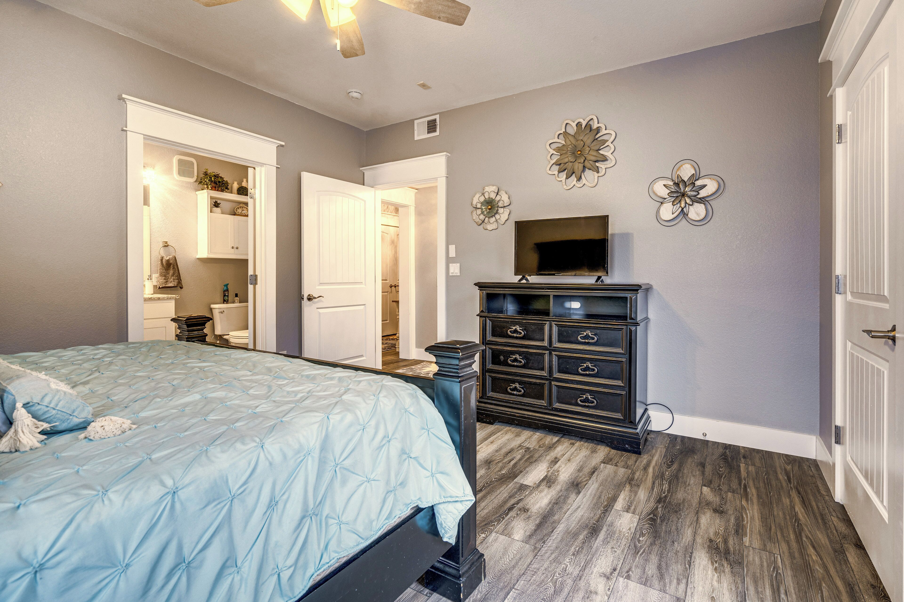A bedroom with a bed, dresser, and a television on the wall.