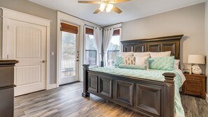 A bedroom with a dark wooden bed, a ceiling fan, and a view of the outdoors through a door.