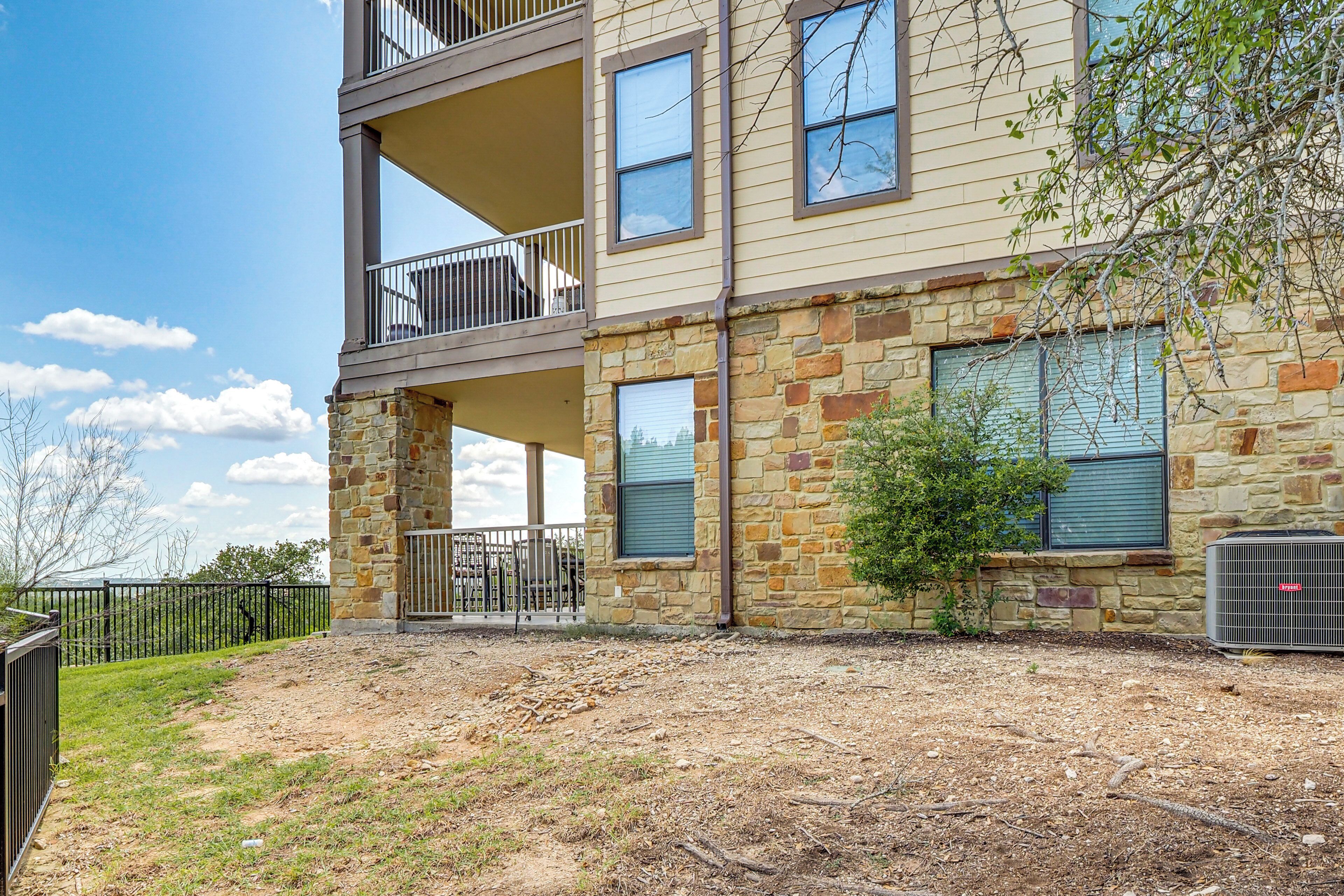 A multi-story building with a stone facade, balconies, and a fenced outdoor area.
