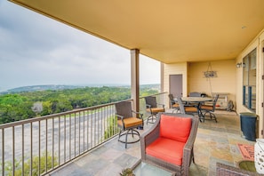 Varanda com móveis de vime, uma mesa e cadeiras, com vista para uma paisagem deslumbrante.