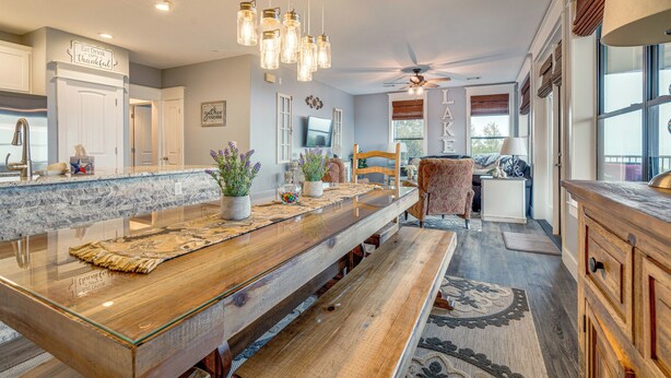 A modern kitchen with a long island, pendant lights, and a ceiling fan.
