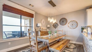 A dining area with a wooden table, chairs, and a bench. There are decorative wall plates and a chandelier.