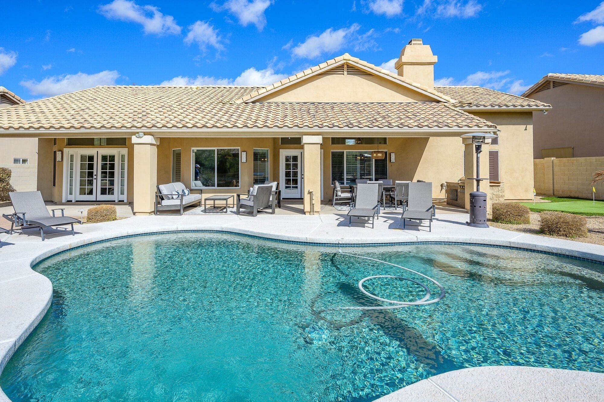 A house with a swimming pool, outdoor furniture, and a covered patio area.