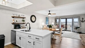 Et moderne køkken med en central ø, et spiseområde med udsigt og en balkon med udsigt.