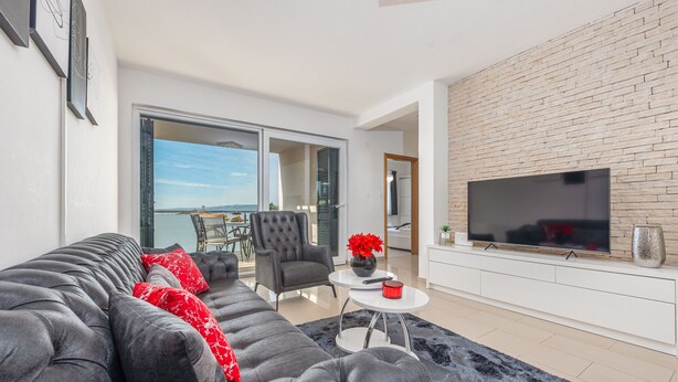 A modern living room with a grey sofa, a flat-screen TV, and a large window. - Villa Ivan (Novigrad)