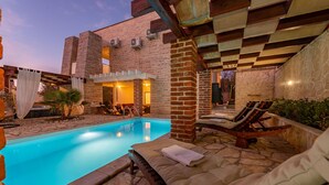 A swimming pool with lounge chairs, a brick building, and a pergola structure. - Villa Ivan (Novigrad)