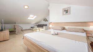 A modern hotel room with a large bed, a desk, a chair, and a small table with a lamp. - Villa Ivan (Novigrad)