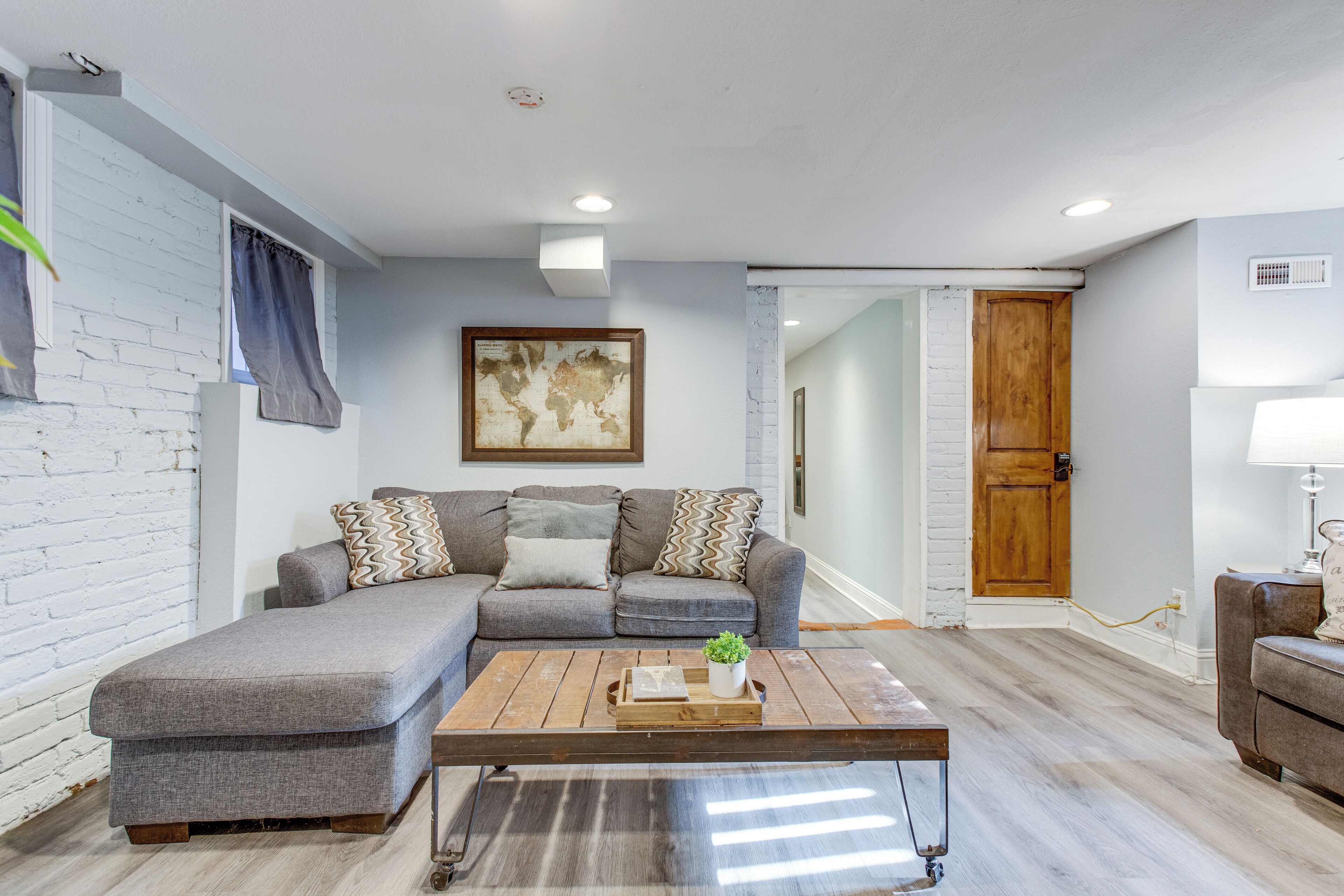 A living room with a sectional sofa, a wooden coffee table, and a world map on the wall.