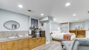Une chambre moderne avec un grand lit, des tables de chevet et un fauteuil recouvert d’un tissu gris.