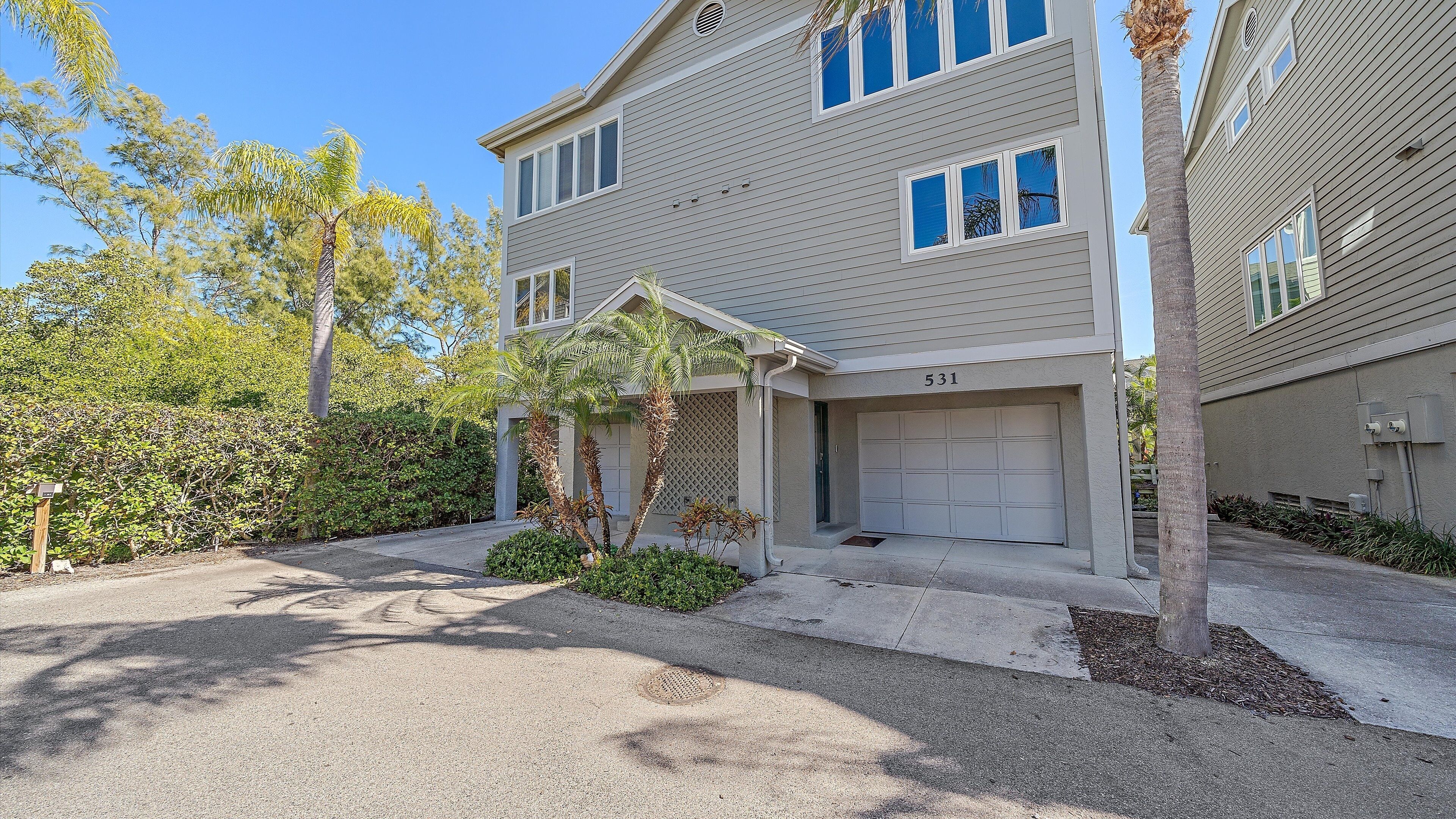 A two-story residential building with a garage, number 531, surrounded by greenery and a clear sky.