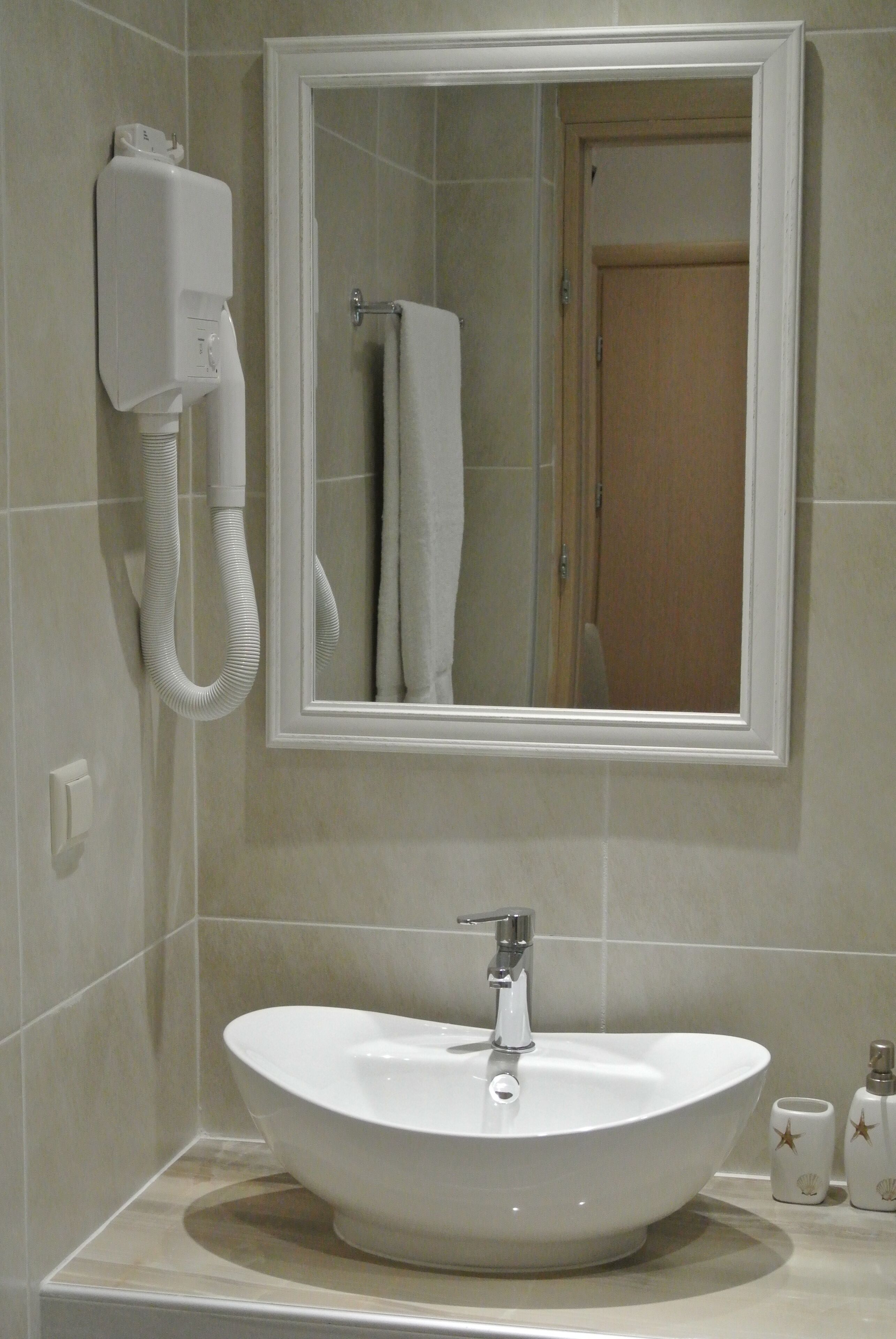 Une salle de bain avec un lavabo blanc, un miroir et un porte-serviettes.