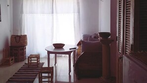 A living room with a sofa, a table with a bowl, a wicker basket, and a wooden cabinet. - On the Beach you see Horses and Quad Riders (Essaouira)