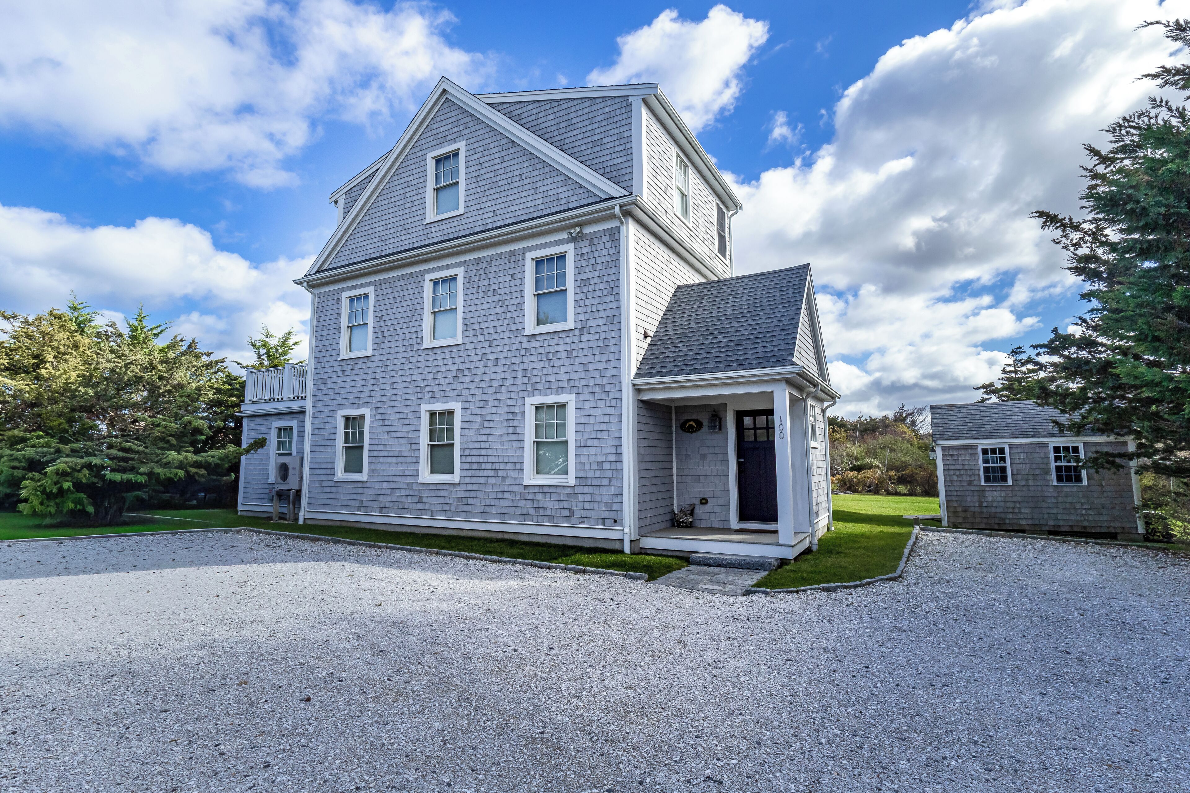 A two-story house with a front porch, a driveway, and a small detached garage.