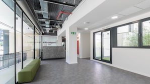 Un interior moderno con un banco verde, paredes de vidrio y un letrero que dice 'micampus'.